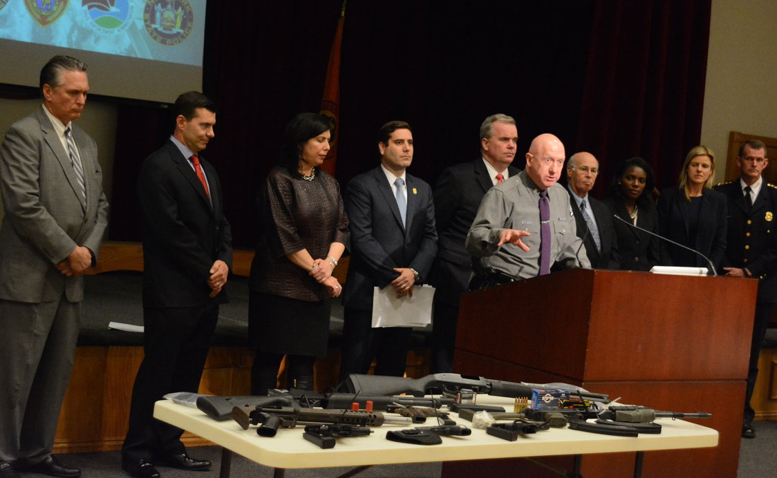 An official gestures to a sampling of the weapons found in the investigation. (Photo by Janelle Clausen) 