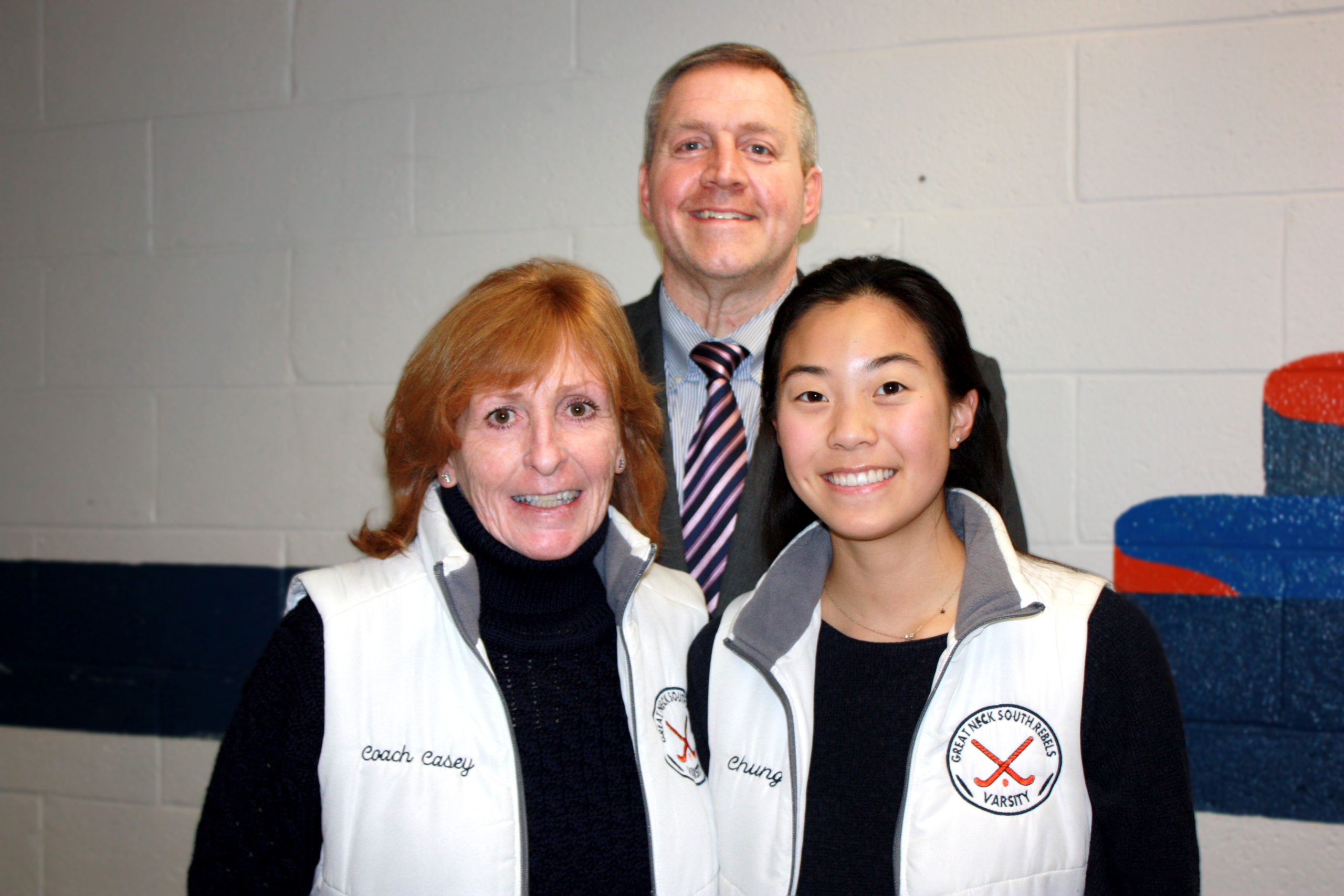 Great Neck South senior Glory Chung is congratulated by Tara Rosenthal, coach of the field hockey team, and Dr. Christopher Gitz, principal of Great Neck South. (Photo courtesy of Great Neck Public Schools)