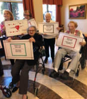 A group of seniors at Atria Cutter Mill show off their signs. (Photo courtesy of Edith Pitashnick)