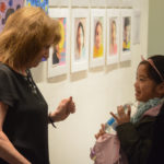 Ellen Schiff, the head of school at the Gold Coast Arts Center, greets one of her students at the opening reception of the Festival of the Arts gallery. (Photo by Janelle Clausen)