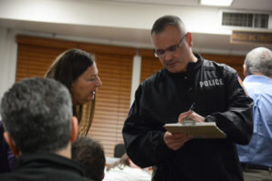 Problem oriented police officer Thomas Brock takes down notes as he speaks to a Great Neck resident at a public safety forum. (Photo by Janelle Clausen)