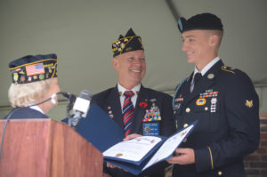 Louise McCann presents Specialist Jeremiah Reuthe of the 101st Airborne, as his father Russell looks on, with two certificates recognizing his presence at the Great Neck Memorial Day Parade to give to his First Sergeant. (Photo by Janelle Clausen)