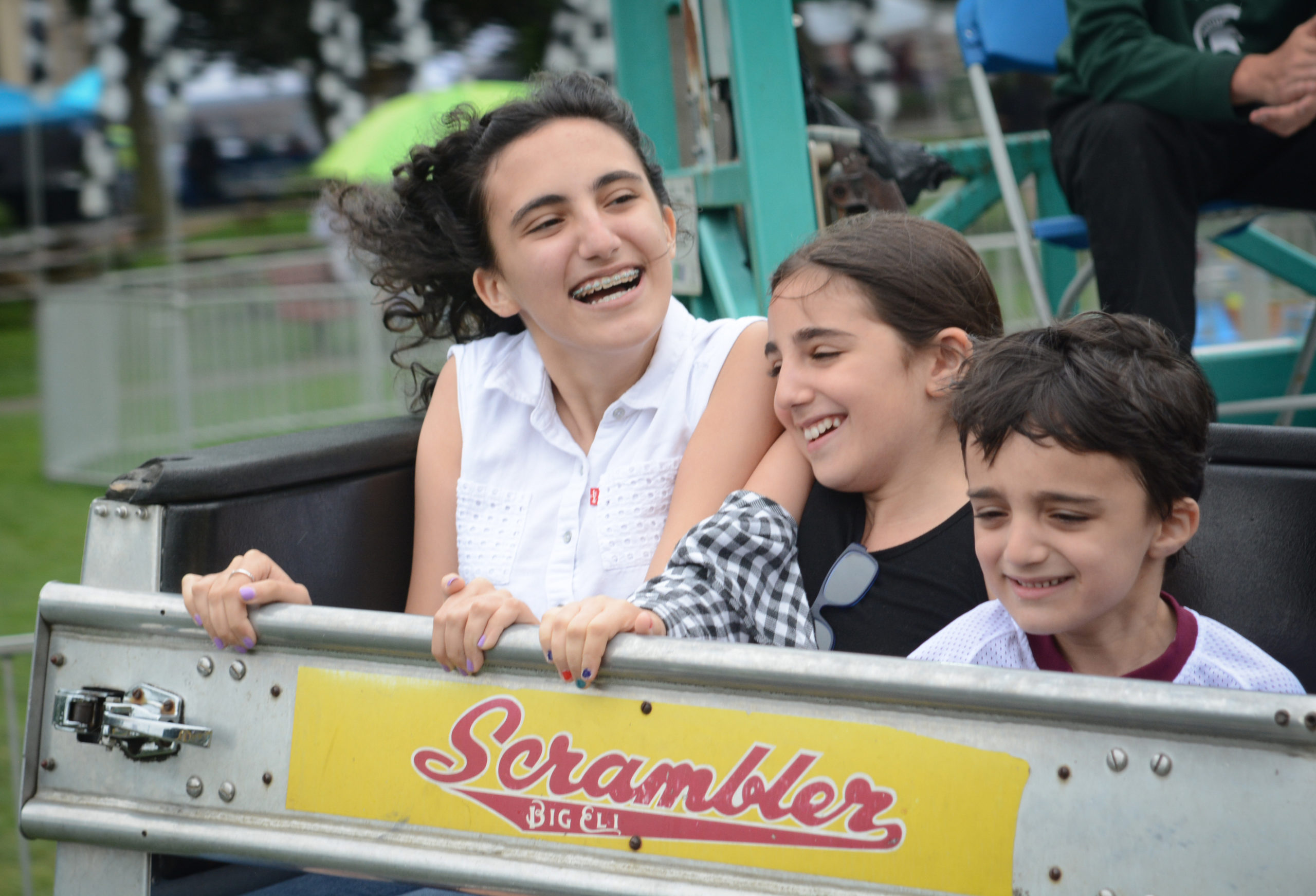 Dana, Sabrina and Kevin Levian, the grandchildren of Norman Namdar, enjoy a ride on the Scrambler at Village Green. (Photo by Janelle Clausen)