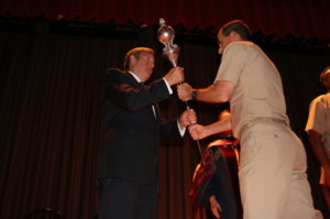 Rear Adm. James A. Helis passes the USMMA Academic Mace to John R. Ballard as he accepts responsibility for the academic program in a ceremony at the Academy on Monday. (Photo courtesy of the U.S. Merchant Marine Academy)
