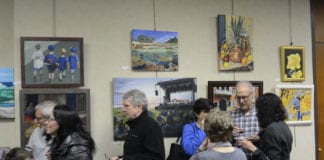 Artists, family and friends examine the work on display in Great Neck Plaza Village Hall. (Photo by Janelle Clausen)